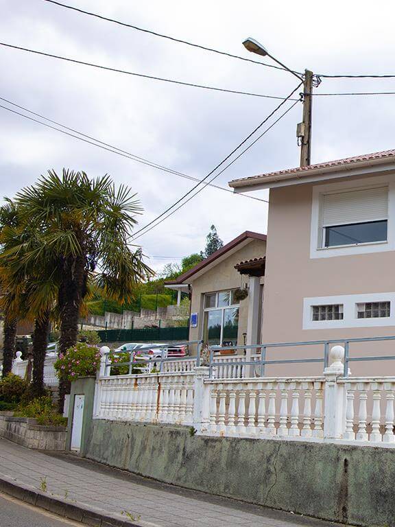 Fachada de la residencia Armayor con dos residentes sentados en la terraza tomando el sol.